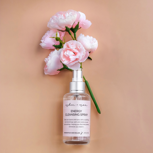 Spray bottle labeled 'Energy Cleansing Spray' with pink flowers on a beige background | Indie + Mae