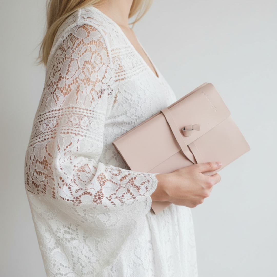 Person wearing a white lace top holding a pink journal against a plain background  | Indie + Mae | Gifts Under $50