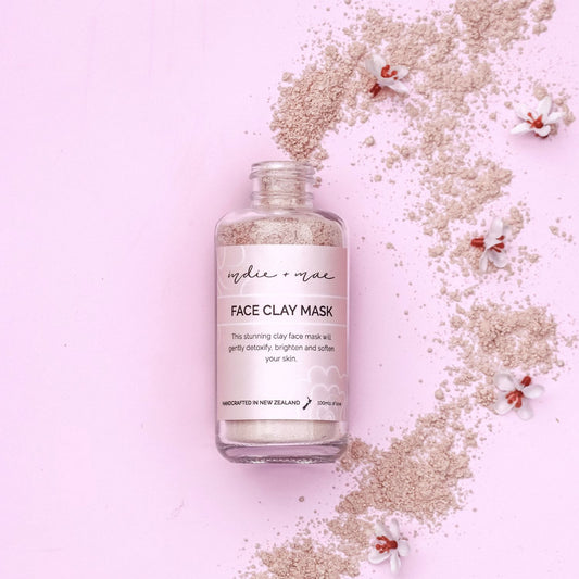 Face clay mask bottle with scattered clay on a pink background | Indie + Mae